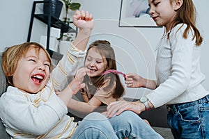 Team of girls ganging up to tickle a boy. One with hands, other with feather.