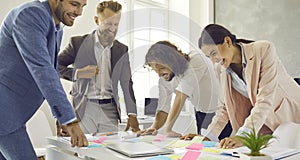 Team of happy business people laughing at something funny while brainstorming in work meeting