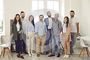 Team of happy confident young and mature business people standing in office and smiling