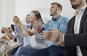 Team of happy people giving round of applause after lecture at public conference