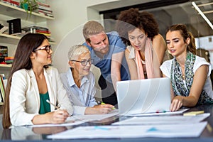 Team of happy successful architects working on construction plans in office.