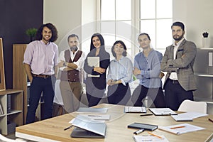 Team of happy successful business professionals standing by window in modern office