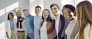 Multiracial team of happy young business people hugging and smiling in their office
