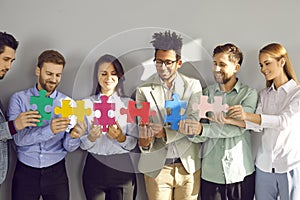 Team of happy young diverse business people connecting colorful jigsaw puzzle pieces