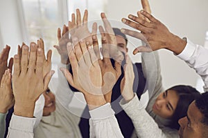 Team of happy young mixed-race business people raising their hands up in the air