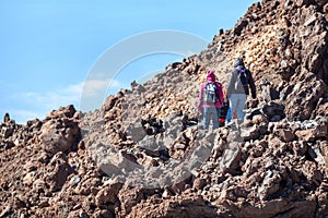 Team of hikers climbing to volcano summit on route No. 10 among the hardened lava flows and shape boulders. Hiking trail to the