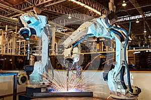 Team industrial robots is welding assembly steel part in car factory