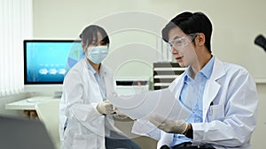 Team of industrial scientists wearing white coats working together in research laboratory
