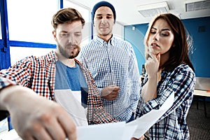 Team job. Photo young businessmans crew working with new startup project in modern loft. Generic design notebook on wood