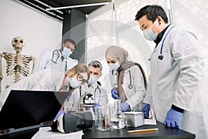 Team of lab workers, veterinarians, bio chemists examining tissues or blood sample using the microscope. Group of