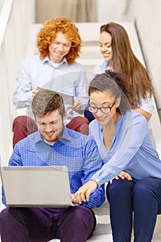 Team with laptop and tablet pc on staircase