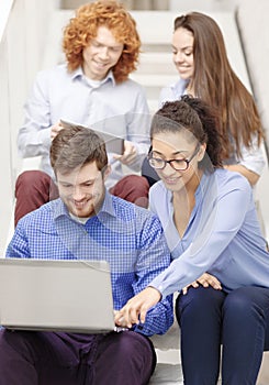 Team with laptop and tablet pc on staircase