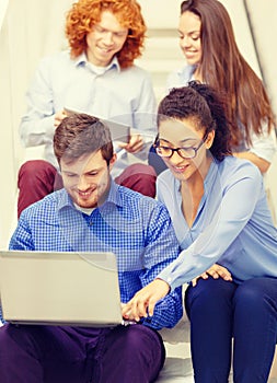 Team with laptop and tablet pc on staircase