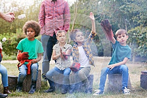 Team Leader With Group Of Children On Outdoor Activity Trip Toasting Marshmallows Over Camp Fire