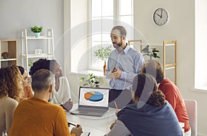 Team leader making presentation in group meeting using pie charts on laptop screen