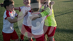 Team of little boys soccer players are embracing