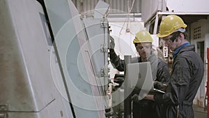 Team maintenance engineer using laptop computer control machine in factory together, industrial and operating.