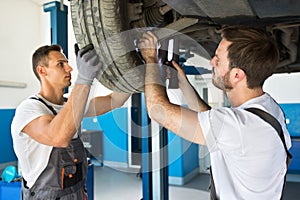 Team of mechanics repair wheel on the car