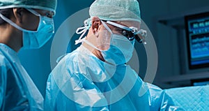 Team of medical doctors performs surgical operation in modern operating room using high-tech technology. Surgeons are