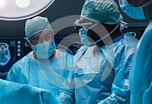 Team of medical doctors performs surgical operation in modern operating room using high-tech technology. Surgeons are