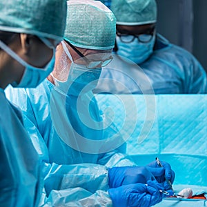 Team of medical doctors performs surgical operation in modern operating room using high-tech technology. Surgeons are