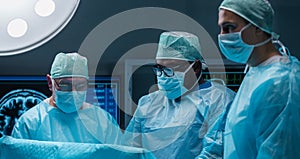 Team of medical doctors performs surgical operation in modern operating room using high-tech technology. Surgeons are