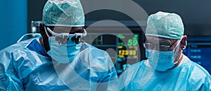 Team of medical doctors performs surgical operation in modern operating room using high-tech technology. Surgeons are