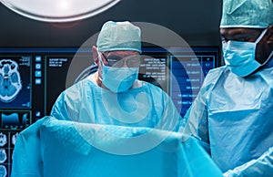 Team of medical doctors performs surgical operation in modern operating room using high-tech technology. Surgeons are