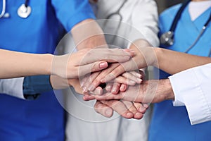 Team of medical doctors putting hands together indoors, closeup