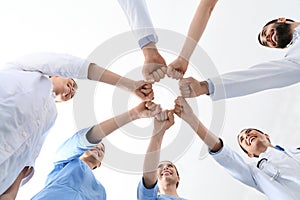 Team of medical doctors putting hands together on white