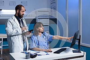 Team of medical specialists looking at computer screen