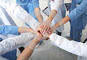 Team of medical workers holding hands together, above view. Unity concept