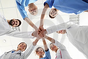 Team of medical workers holding hands together in hospitaÐ´. Unity concept