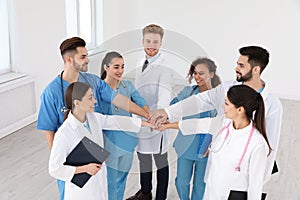 Team of medical workers holding hands together in hospital