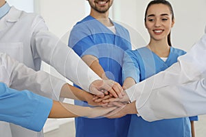 Team of medical workers holding hands together indoors