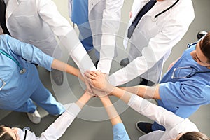 Team of medical workers holding hands together indoors, top view