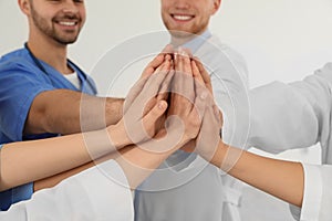 Team of medical workers holding hands together on light background. Unity concept