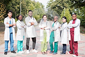 Team of mixed race doctors. Group of young people of different gender in colored medical clothes, standing on the street, on the