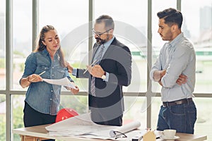 Team of multiethnic architects working on construction plans in meeting room. Engineers discussing on project in office. Mature