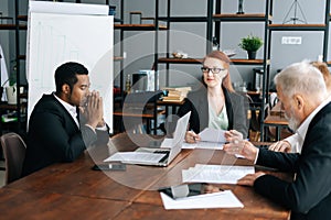 Team of multiracial business people listening female leader explaining project strategy at company briefing table.