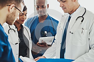 Team of multiracial doctors reading patient notes photo