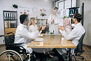 Multiracial doctors smiling and applauding after meeting