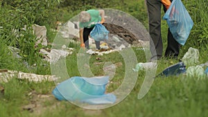 Team of nature activists in eco T-shirts picking up plastic trash in park. Recycle, earth pollution