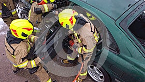 Team off Firefighters trying to cut open car door to save person involved in the accident