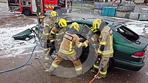 Team off Firefighters trying to cut open car door to save person involved in the accident