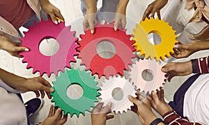 Team of people holding and connecting gears showing concept of teamwork and success