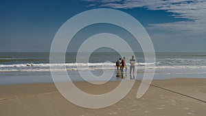 A team of people pulls a fishing net out of the ocean.