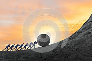 Team of people pushing stone uphill