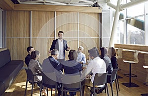 Team of people sitting in office, meeting with business coach and listening to his talk