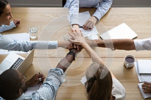 Team people stacking hands together over table engaged in teambuilding photo